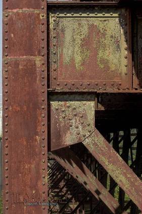the rusting brace of a railroad bridge