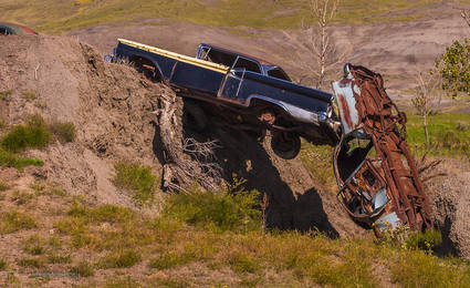 two wrecked cars on a washed out berm